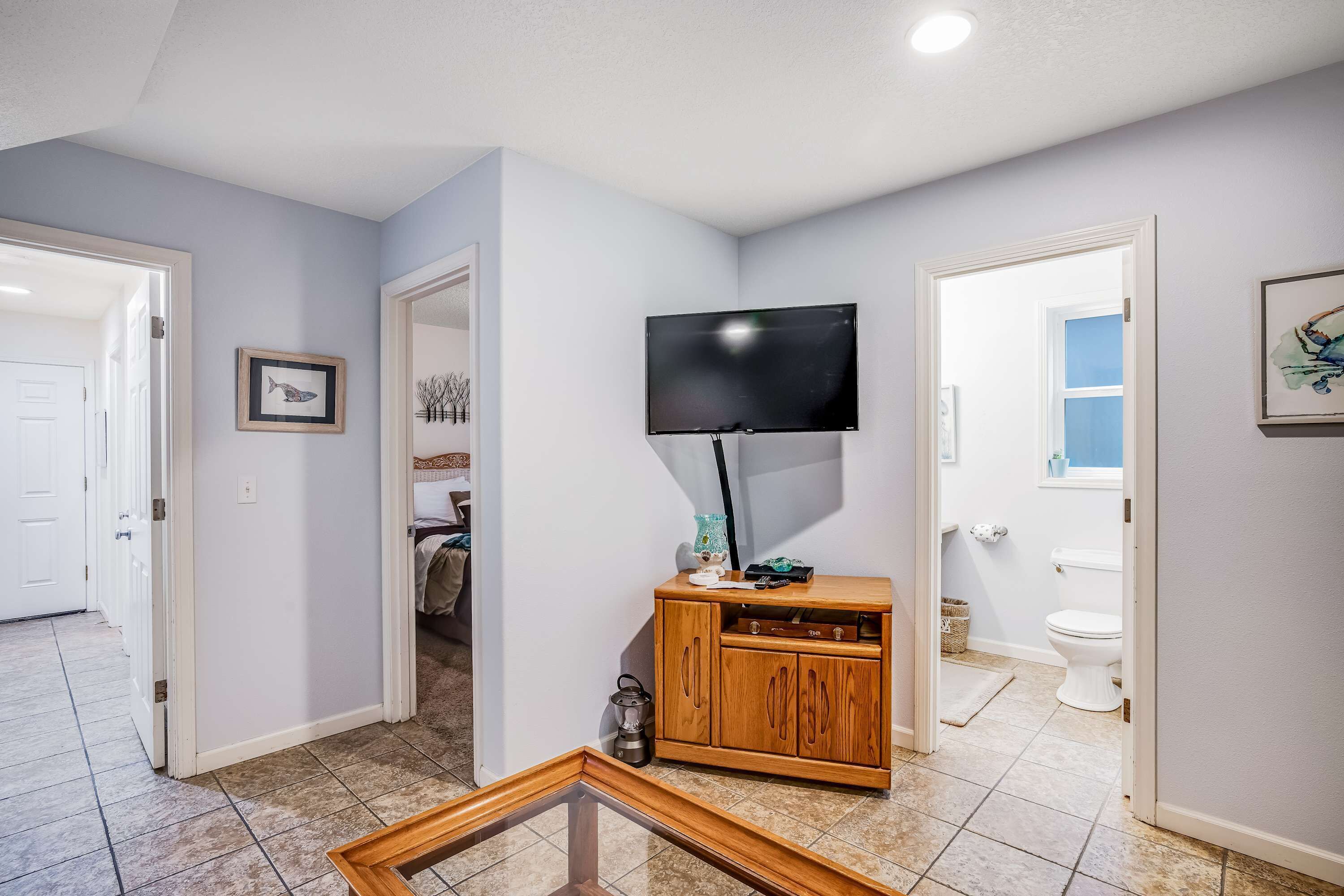 A hallway with a wooden cabinet, a flat-screen TV, and a framed picture on the wall.