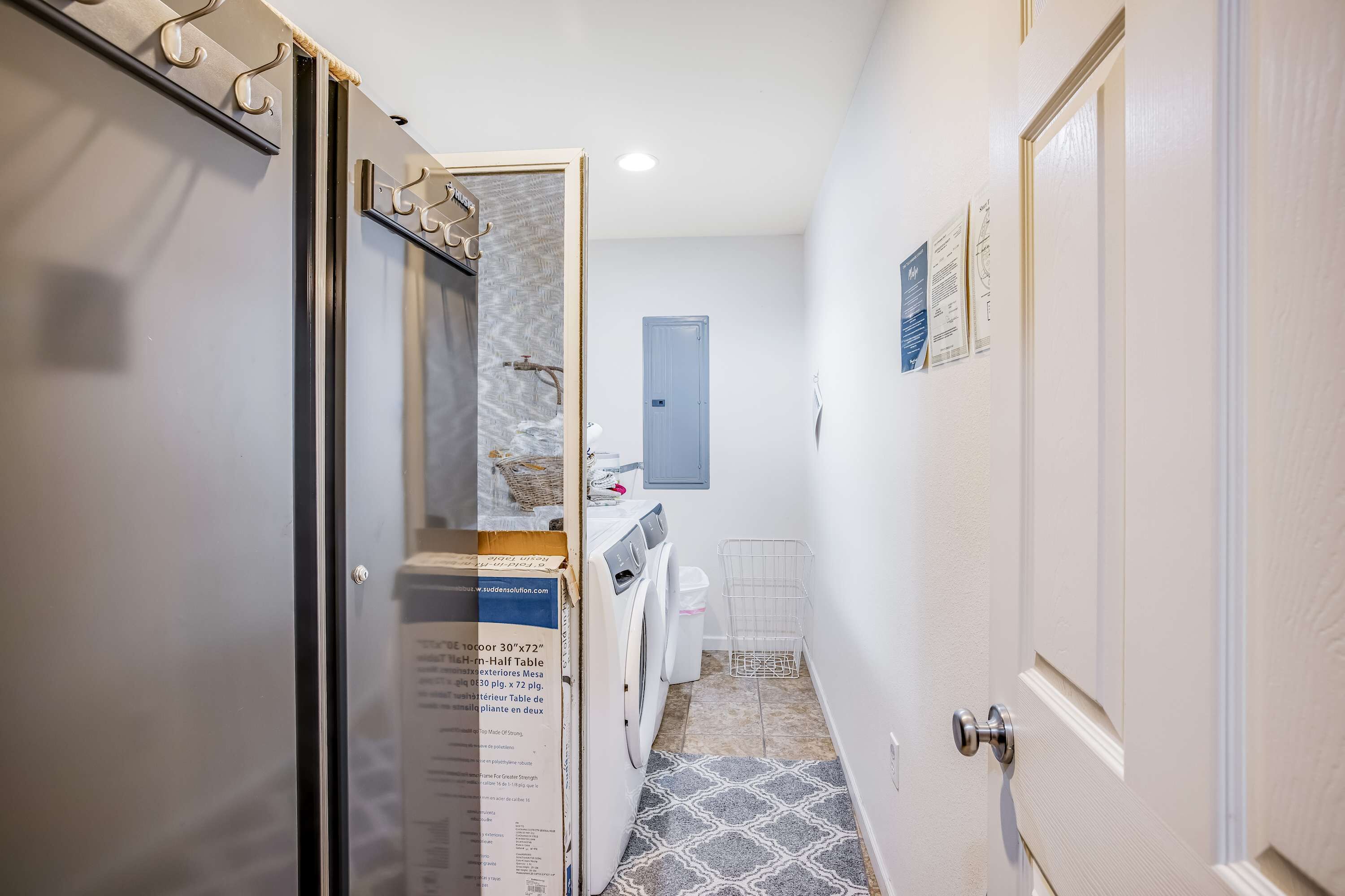 Un corridoio stretto con lavatrice, una porta dotata di porta asciugamani e pavimento decorato.