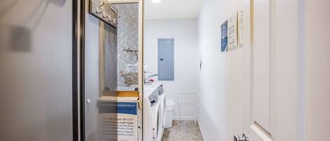 Un corridoio stretto con lavatrice, una porta dotata di porta asciugamani e pavimento decorato.