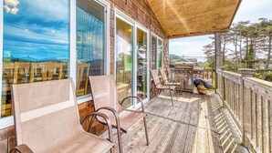 A covered outdoor deck with wooden railings, large windows, and outdoor furniture. - Ocean Views and Modern Interior Close to Rockaway Beach Dogs OK (Rockaway Beach)