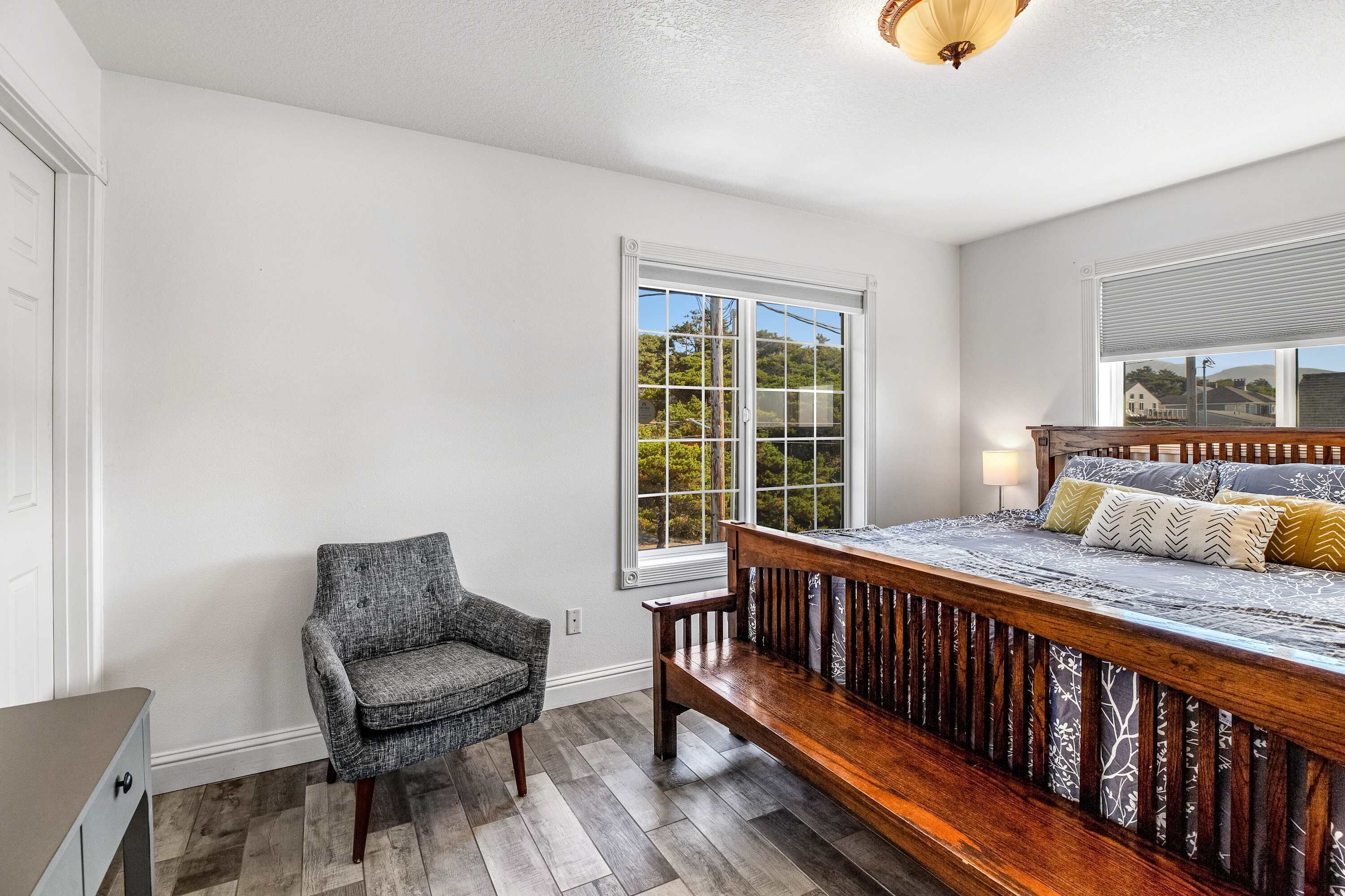 Une chambre avec un grand lit, une chaise et une fenêtre donnant sur un paysage verdoyant.