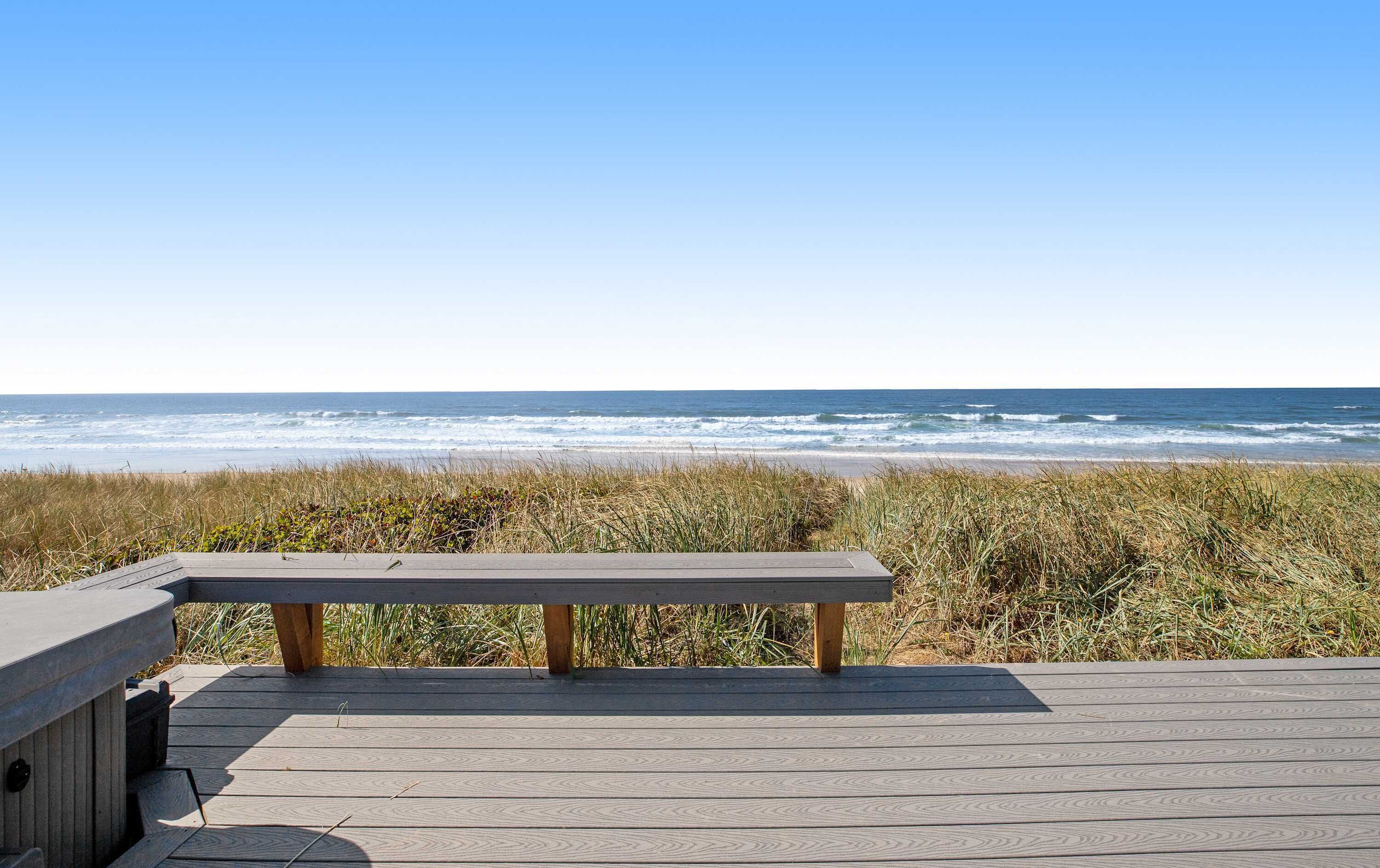 Eine Holzterrasse mit einer Bank mit Blick auf einen Strand.