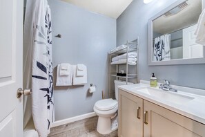Une salle de bain comprenant des toilettes, un lavabo, un miroir et un porte-serviettes.