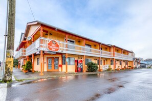 Un motel à deux étages, à la façade rouge et blanche, doté d’un balcon au deuxième étage et d’un comptoir d’accueil bien visible.