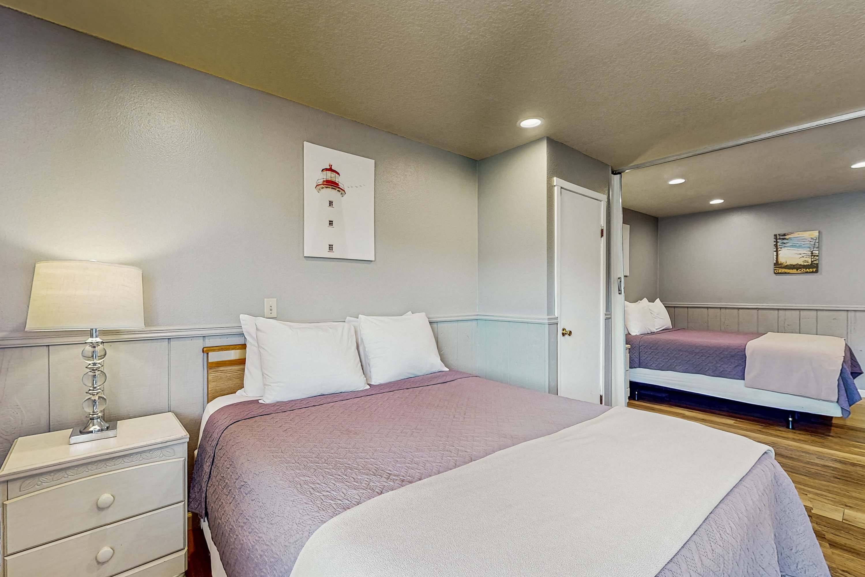 Une chambre d’hôtel avec deux lits, une table de chevet, une lampe et un tableau encadré au mur.