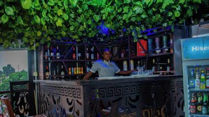 Un espace bar agrémenté d’un plafond décoratif, d’étagères remplies de bouteilles et d’un distributeur automatique.