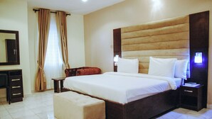 Une chambre d’hôtel avec un grand lit, une table de chevet, un bureau et une chaise.