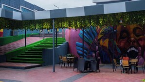 Une cour intérieure ornée d’une fresque murale, dotée d’un espace pour s’asseoir à l’extérieur et d’un escalier.