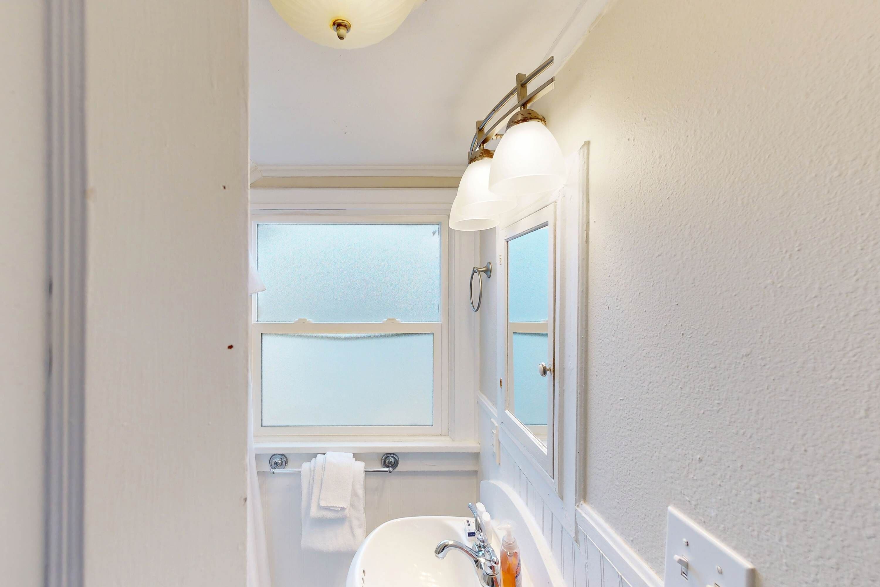 Een badkamer met een witte wastafel, een spiegel en etalageglas ramen.