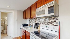 Una cocina con gabinetes de madera, microondas, cafetera y lavavajillas.