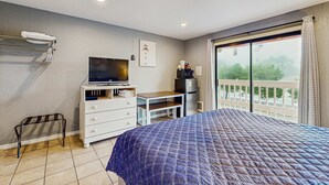 A bedroom with a bed, a TV, a desk, and a balcony with a view. - Dog Friendly Room Located Near the Beach and Downtown (Rockaway Beach)
