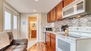 A compact kitchen with wooden cabinets, a microwave, and a stove. - Four Dog Friendly Rentals Near Beach Access Ideal for Multi Families (Rockaway Beach)