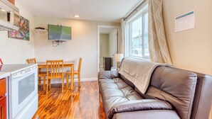 A compact living space with a kitchenette, a sofa, a dining table with chairs, and a television. - Four Dog Friendly Rentals Near Beach Access Ideal for Multi Families (Rockaway Beach)