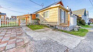 A single-story house with a front porch, a picket fence, and a paved driveway. - Four Dog Friendly Rentals Near Beach Access Ideal for Multi Families (Rockaway Beach)