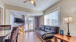 A modern living room with a sofa, a dining table with chairs, a television, and a ceiling fan. - Four Dog Friendly Rentals Near Beach Access Ideal for Multi Families (Rockaway Beach)