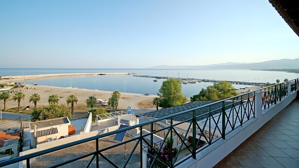 A coastal view from a balcony with a railing, a beach, and boats in the distance. - Apartment 'A View From The Attic Window' with Sea View, Wi-Fi and Air Conditioning (Kyparissia)