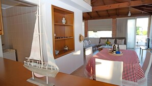 A model sailboat on a table, a dining area with a checkered tablecloth, and a cozy seating area with a sofa and a window. - Apartment 'A View From The Attic Window' with Sea View, Wi-Fi and Air Conditioning (Kyparissia)