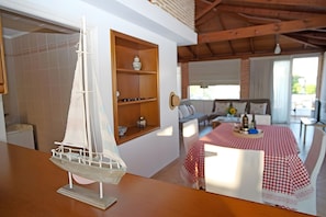 A model sailboat on a table, a dining area with a checkered tablecloth, and a cozy seating area with a sofa and a window.