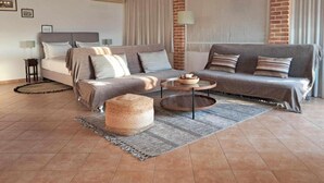 A cozy room with a bed, a sofa, a round coffee table, and a small ottoman. - Apartment 'A View From The Attic Window' with Sea View, Wi-Fi and Air Conditioning (Kyparissia)