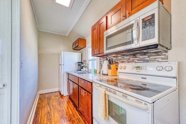 A compact kitchen with wooden cabinets, a microwave, an oven, and a sink. - Dog Friendly Triplex 3 private apartments Easy Walk to the Beach and Town (Rockaway Beach)