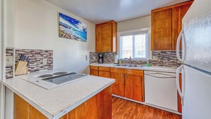 A kitchen with wooden cabinets, a white refrigerator, and a tiled backsplash. - Dog Friendly Triplex 3 private apartments Easy Walk to the Beach and Town (Rockaway Beach)