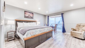 A bedroom with a bed, bedside tables, a chair, and a view of the outdoors. - Dog friendly motel with kitchens and kitchenettes and WiFi walk to the beach (Rockaway Beach)