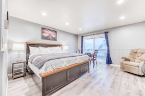 A bedroom with a bed, bedside tables, a chair, and a view of the outdoors. - Dog friendly motel with kitchens and kitchenettes and WiFi walk to the beach (Rockaway Beach)