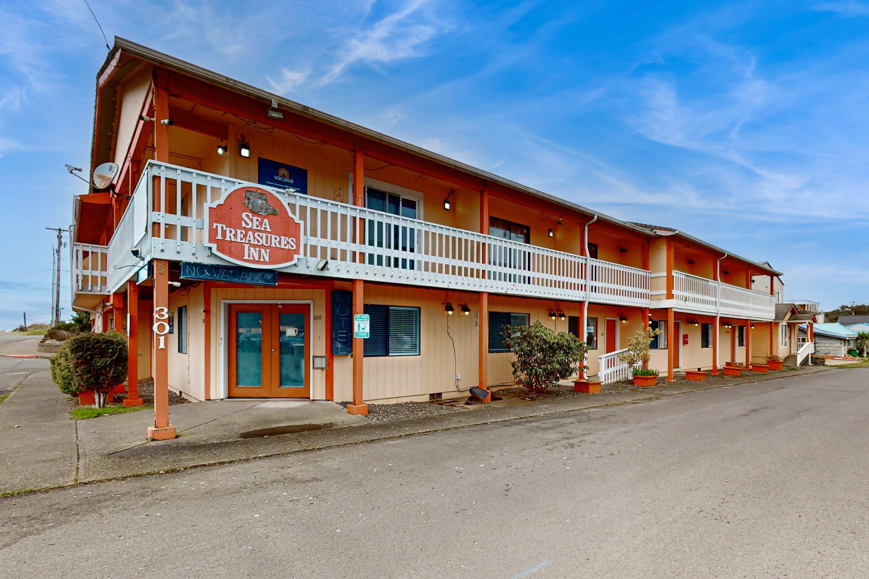 Un motel de dos pisos con un balcón en el segundo piso, un letrero que dice 'Sea Treasures Inn' y el número '301' en el edificio.