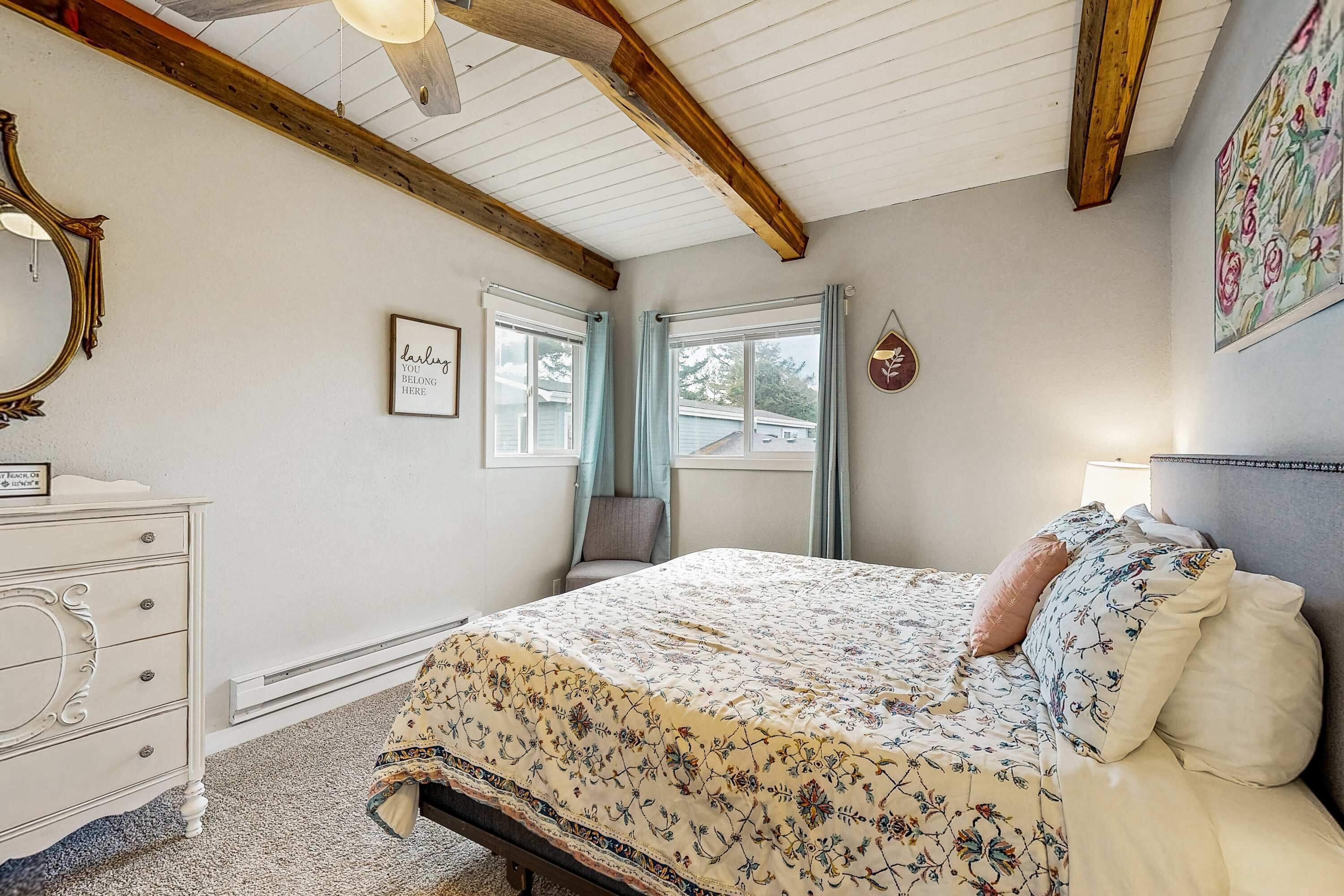 A bedroom with a bed, dresser, and a window with curtains.