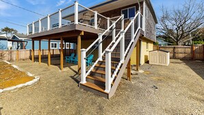 Een tweelaags huis met een overdekte patio, een trap en buiten zitplaatsen.
