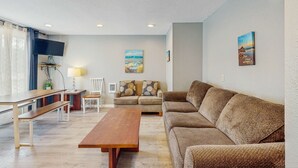 A living room with a sofa, a coffee table, a TV, and a painting on the wall. - Dog Friendly Room with Kitchen Located Near the Beach and Downtown (Rockaway Beach)