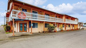 Un motel à deux étages avec un balcon au rez-de-chaussée, une enseigne indiquant « Sea Treasures Inn » et une porte d’entrée bien visible.