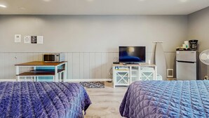 A hotel room with two beds, a television, a microwave, a refrigerator, and a small table with a chair. - Bright Room Near the Beach and Downtown Dogs OK (Rockaway Beach)