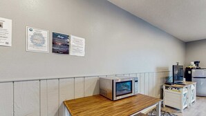 A kitchenette with a microwave on a wooden table, a refrigerator, and a small cabinet with a coffee machine. - Bright Room Near the Beach and Downtown Dogs OK (Rockaway Beach)