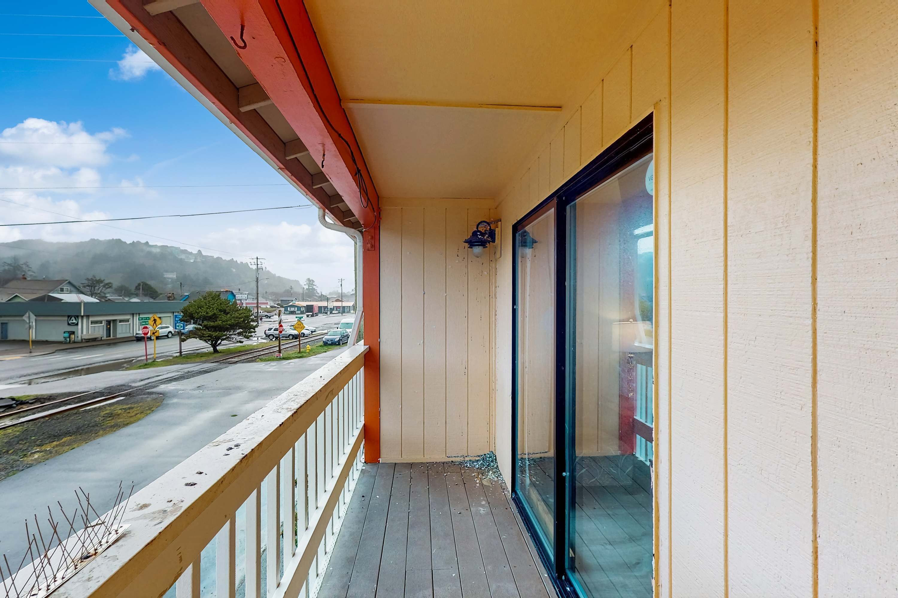 A balcony with a wooden floor, a red railing, and a glass door.