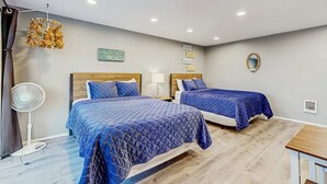 Une chambre d’hôtel avec deux lits, un ventilateur, une petite table et un miroir fixé au mur.