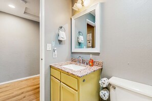 Un baño con lavamanos, espejo e inodoro.