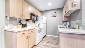 Una cocina compacta con armarios de madera, microondas, estufa y refrigerador.
