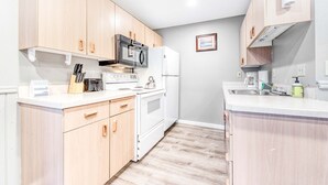 A compact kitchen with light wood cabinets, a microwave, stove, and a refrigerator. - Dog Friendly Room with Kitchen Located Near the Beach and Downtown (Rockaway Beach)