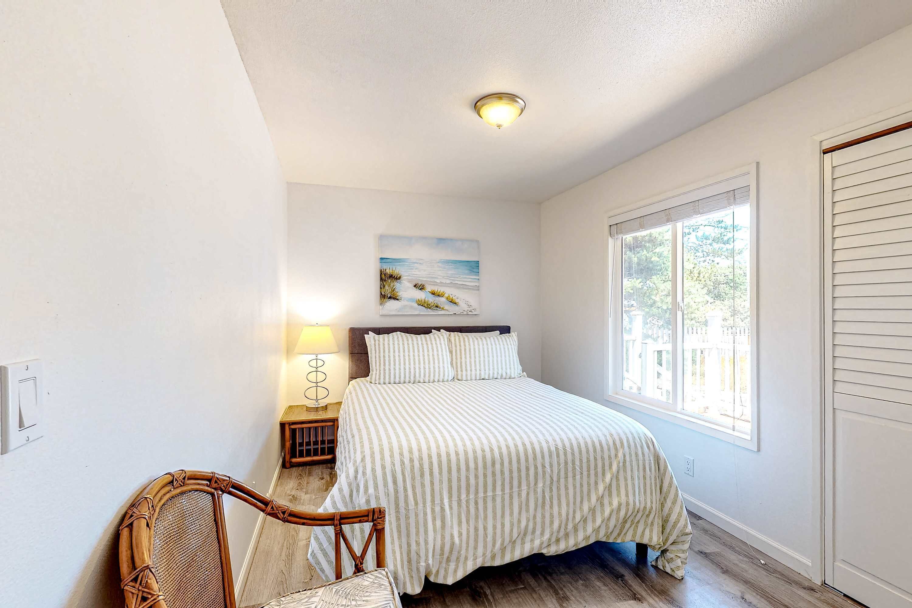 A bedroom with a bed, a chair, a nightstand, a lamp, a window, and a door.