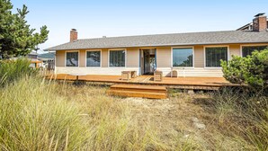 Una casa moderna con terraza de madera, ventanas grandes y una chimenea de ladrillo.