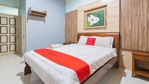 A hotel room with a bed, a wooden headboard, a wall-mounted picture frame, and a small wooden shelf. - Sangkan Hurip Kuningan Hiyel (Cilimus)