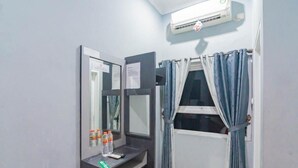 A small bathroom with a mirror, a shelf with toiletries, a window with curtains, and an air conditioning unit. - Sangkan Hurip Kuningan Hiyel (Cilimus)