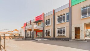 A modern hotel with a prominent red sign, multiple windows, and a covered entrance area. - Sangkan Hurip Kuningan Hiyel (Cilimus)