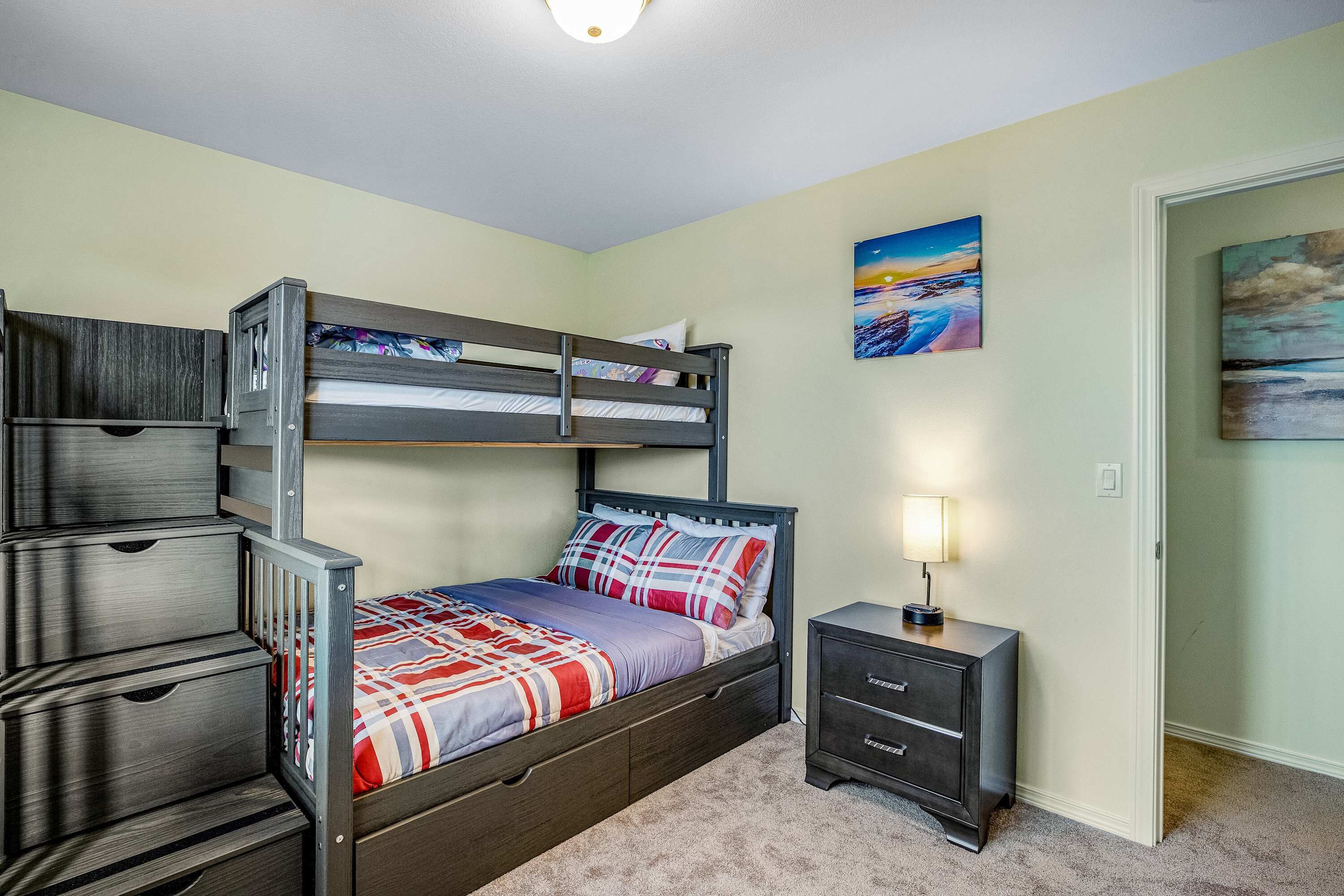 A bunk bed with drawers, a bedside table, and a lamp.
