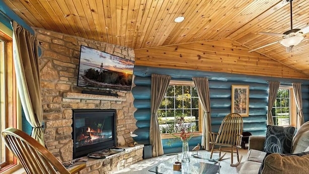 Un salon chaleureux avec une cheminée en pierre, un plafond en bois et de grandes fenêtres.