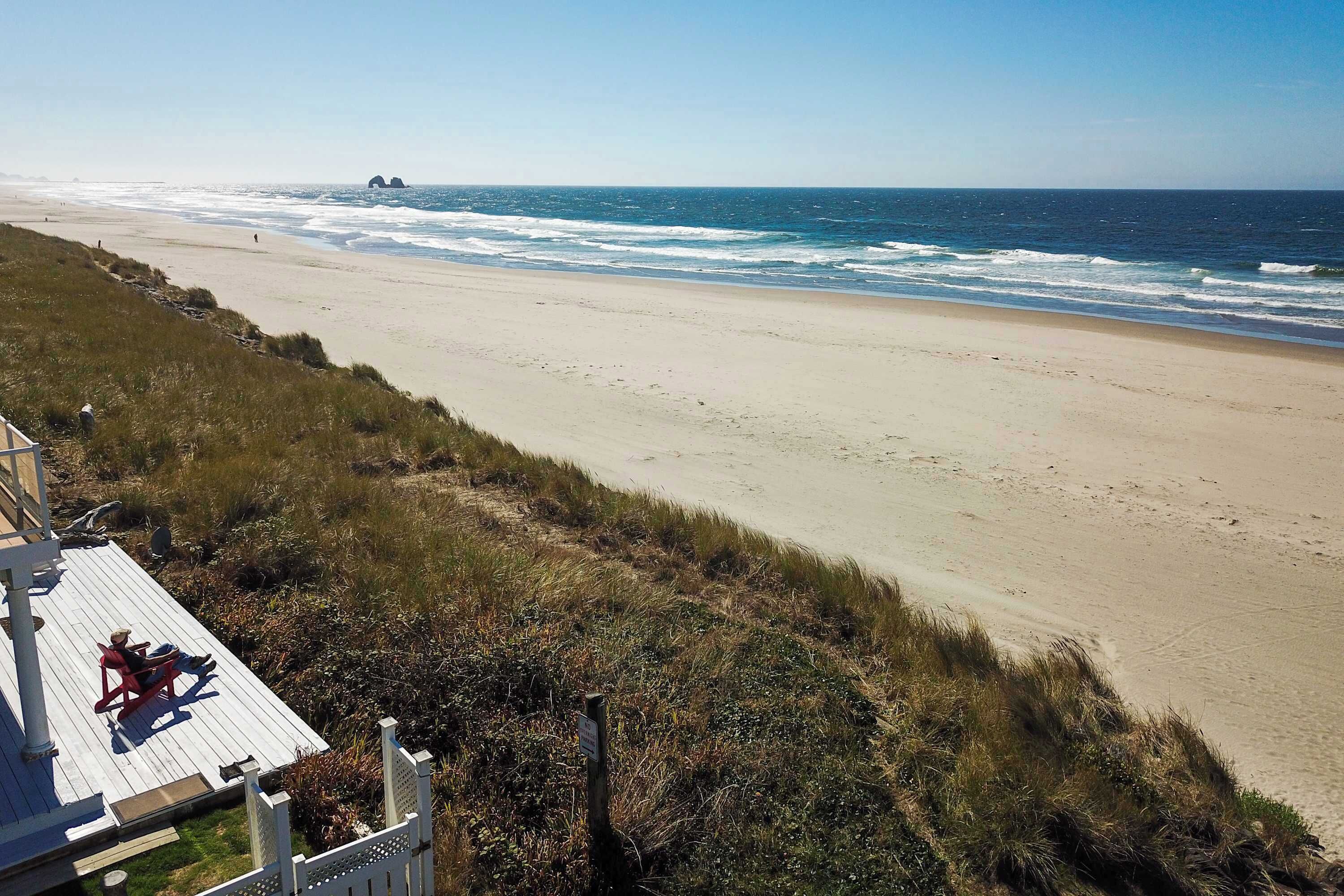 A beach with a wooden deck and a view of the ocean.
