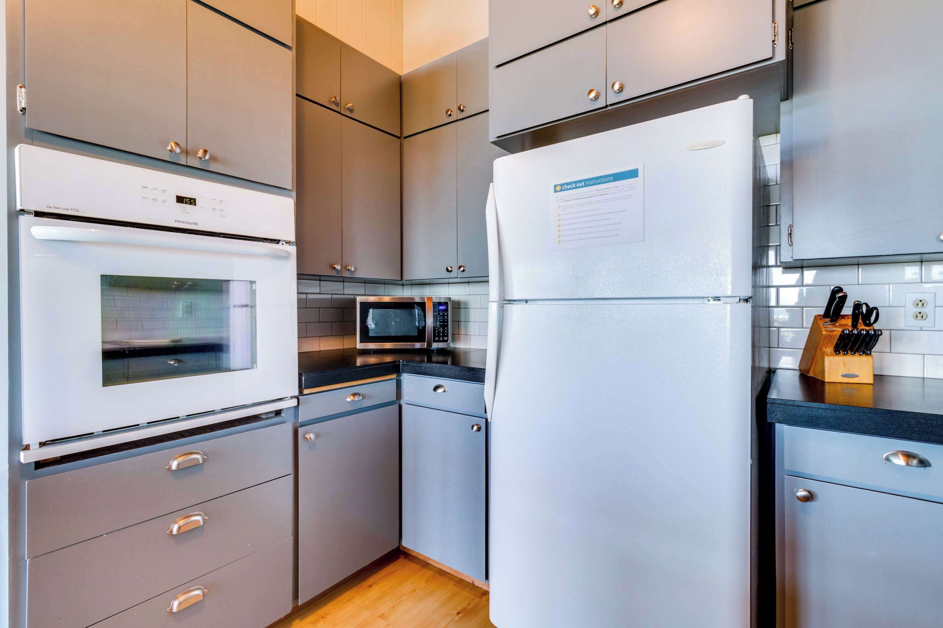 Eine moderne Küche mit grauen Schränken, einem weißen Kühlschrank, einer Mikrowelle und einem eingebauten Backofen.
