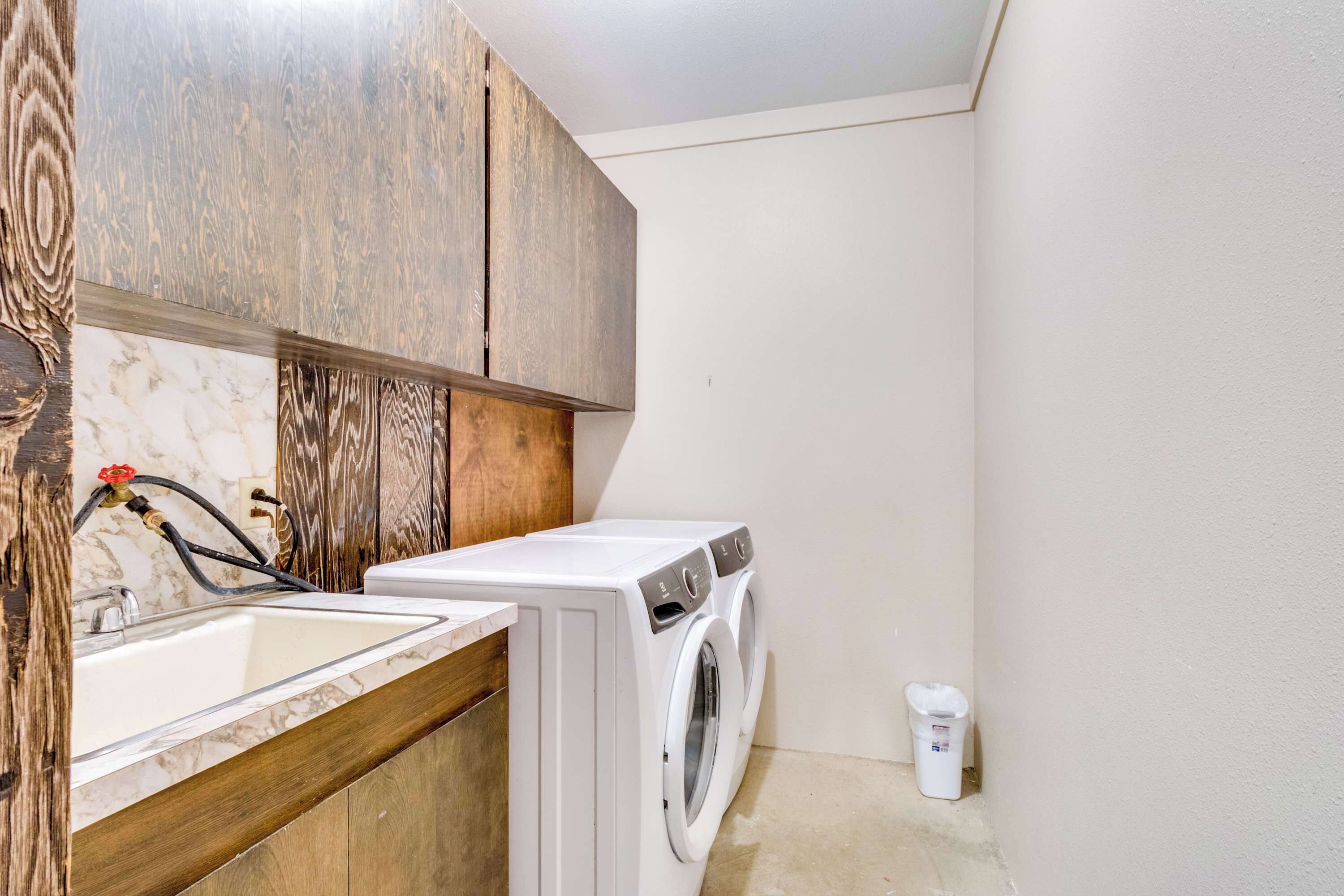 A compact laundry area with a washing machine, a sink, and wooden cabinets.