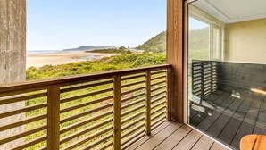 Un balcon avec vue sur la plage et les collines.